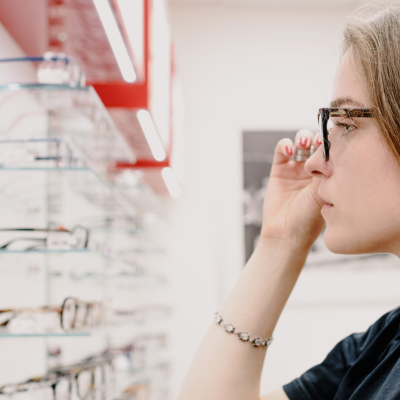 Illustration du pack analyse de Lunettes, une fille essaye des lunettes chez l'opticien